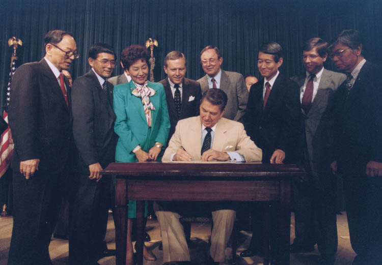 President Reagan signs the Civil Liberties Act of 1988 in an official ceremony.