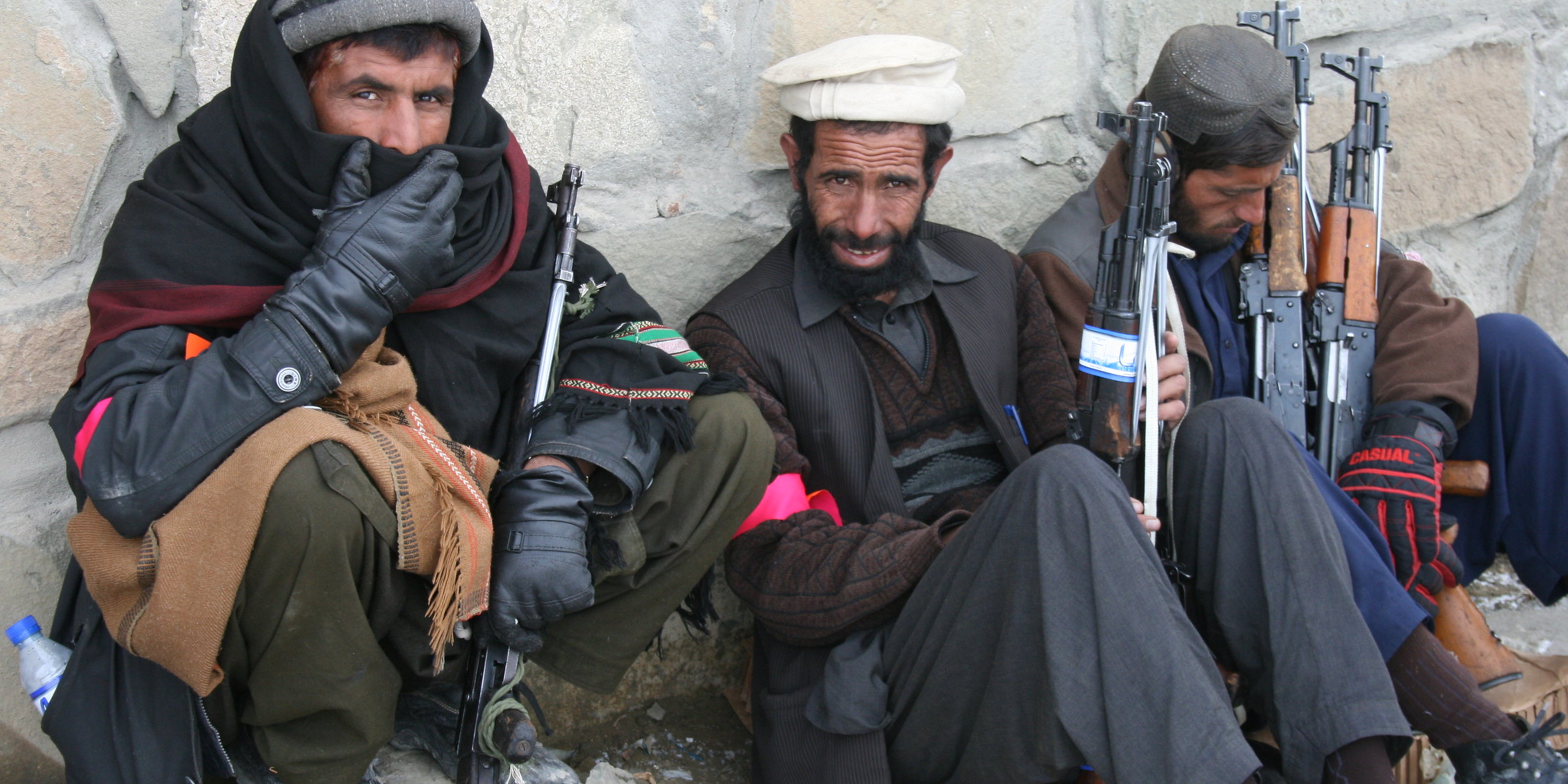 Three Afghan police trainees, sitting on ground with guns