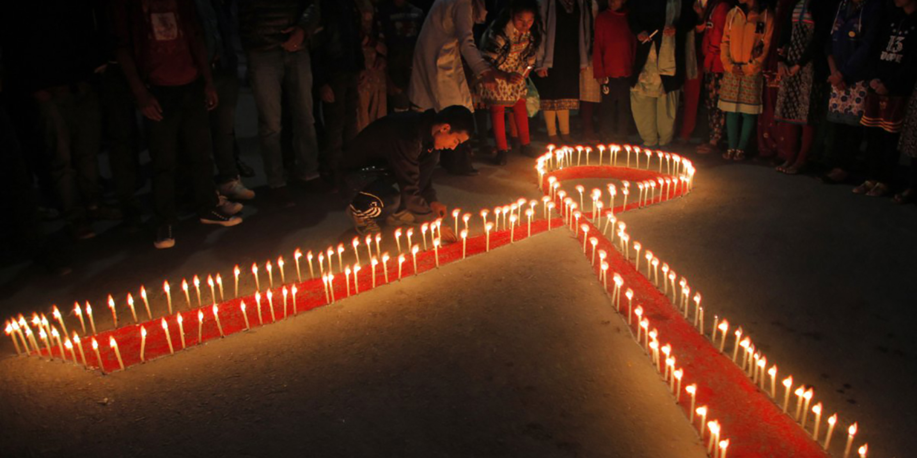 A red AIDS ribbon outlined in candles
