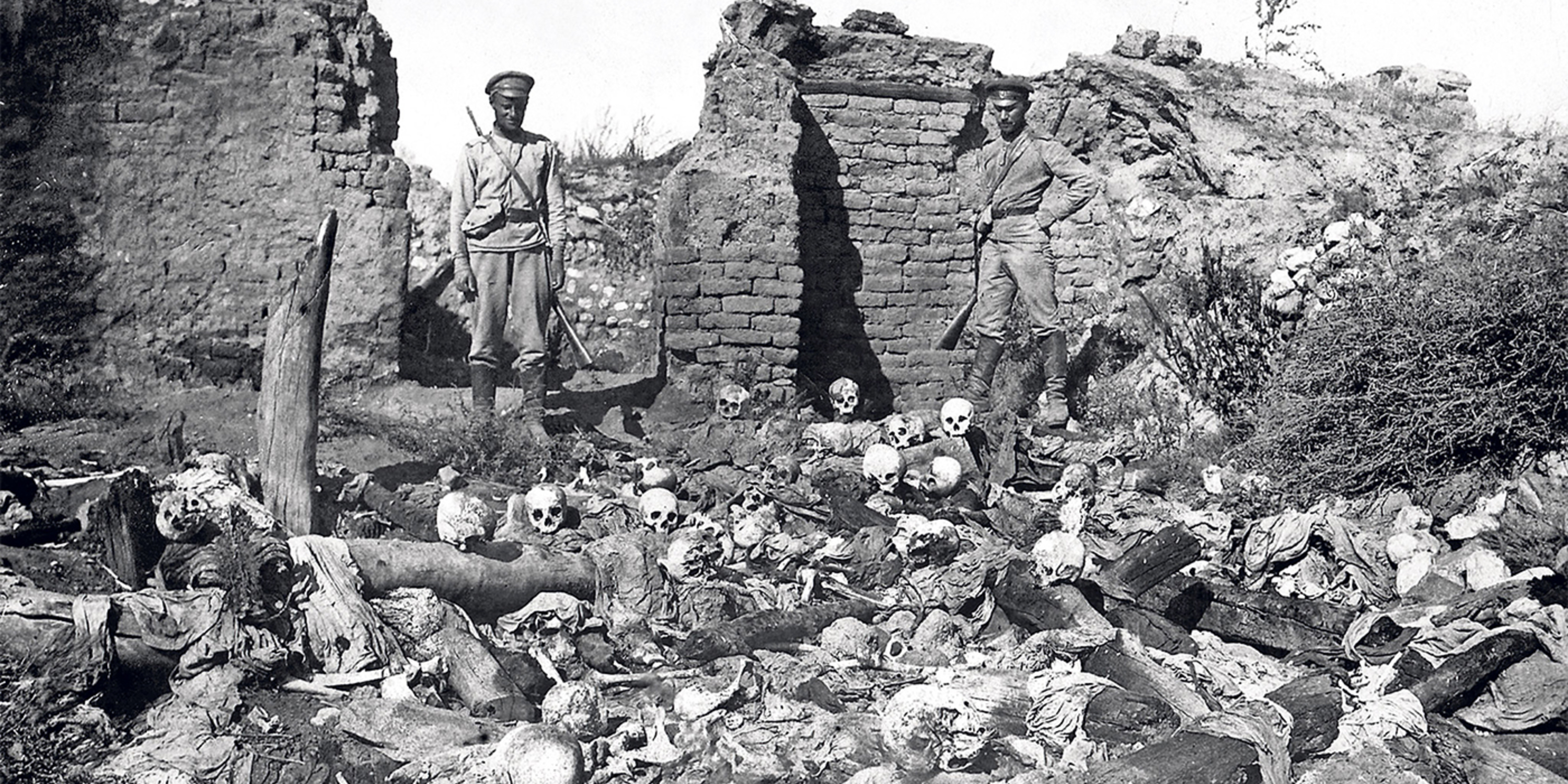 Turkish soldiers standing over skeletal remains during Armenian Genocide