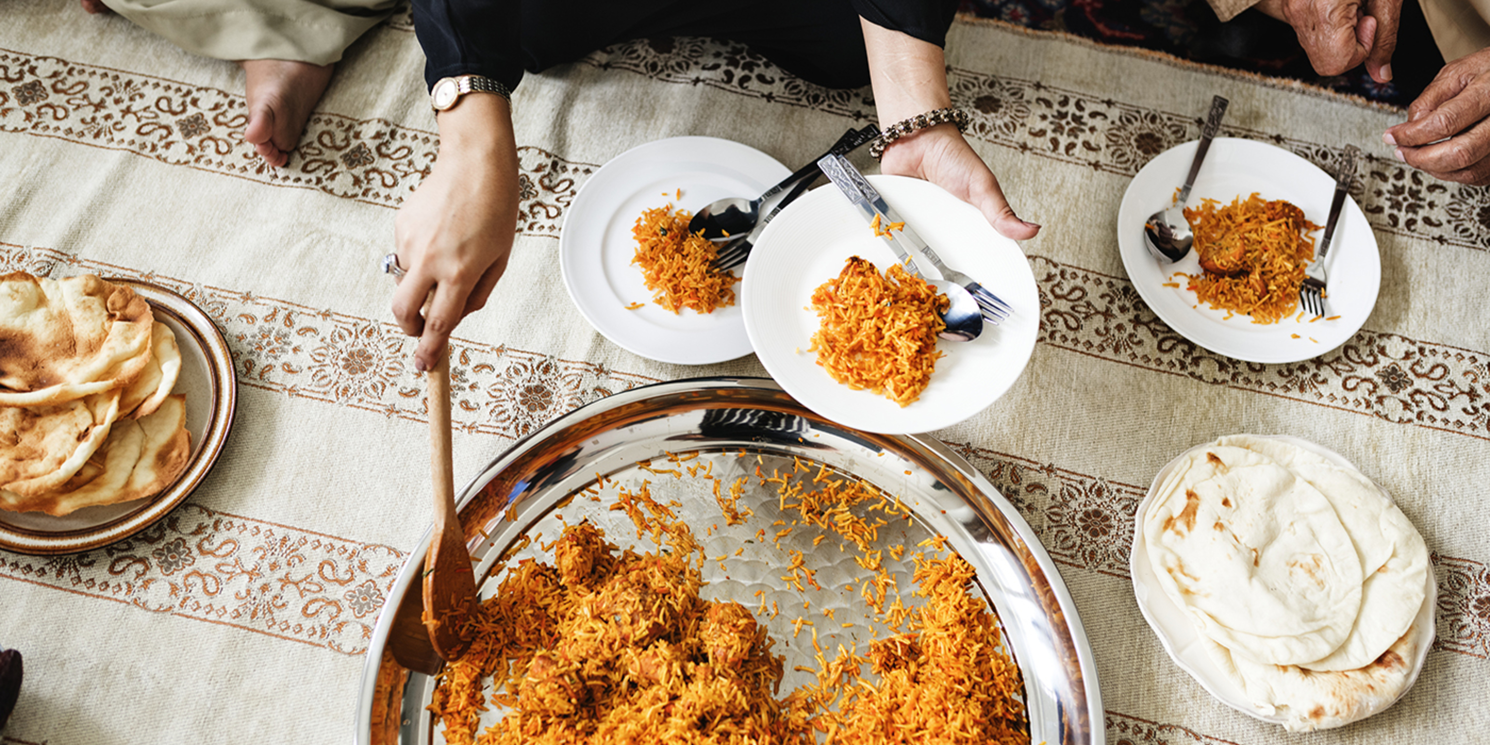 Top view of person serving themself a rice dish from a table of food