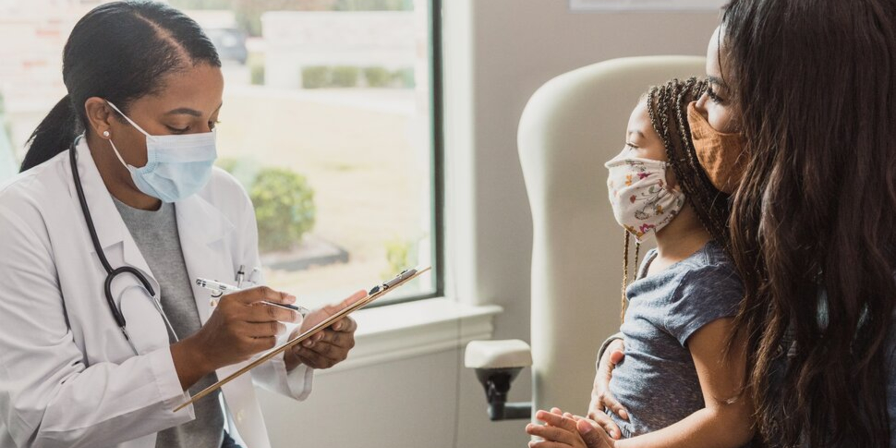 a Black doctor talking with a Black woman and a female Black child