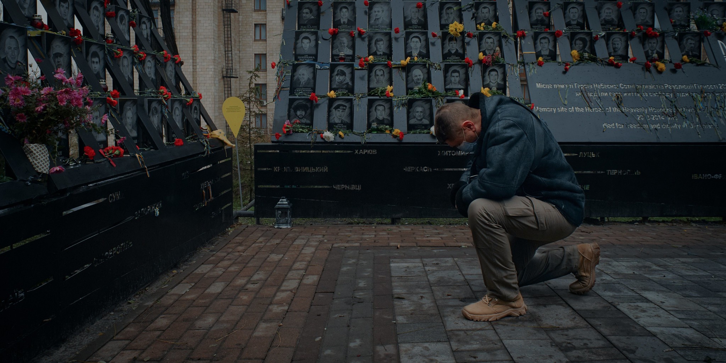 a man kneeling down near tributes to fallen heroes