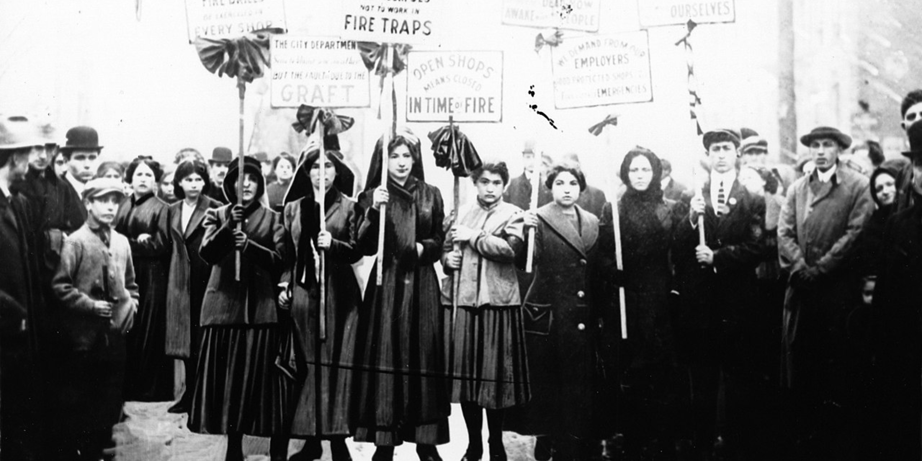 Mourners picket after the Triangle fire. Their signs, hung with black crepe, accuse shop owners of graft, locked doors, and managing workers in fire traps.