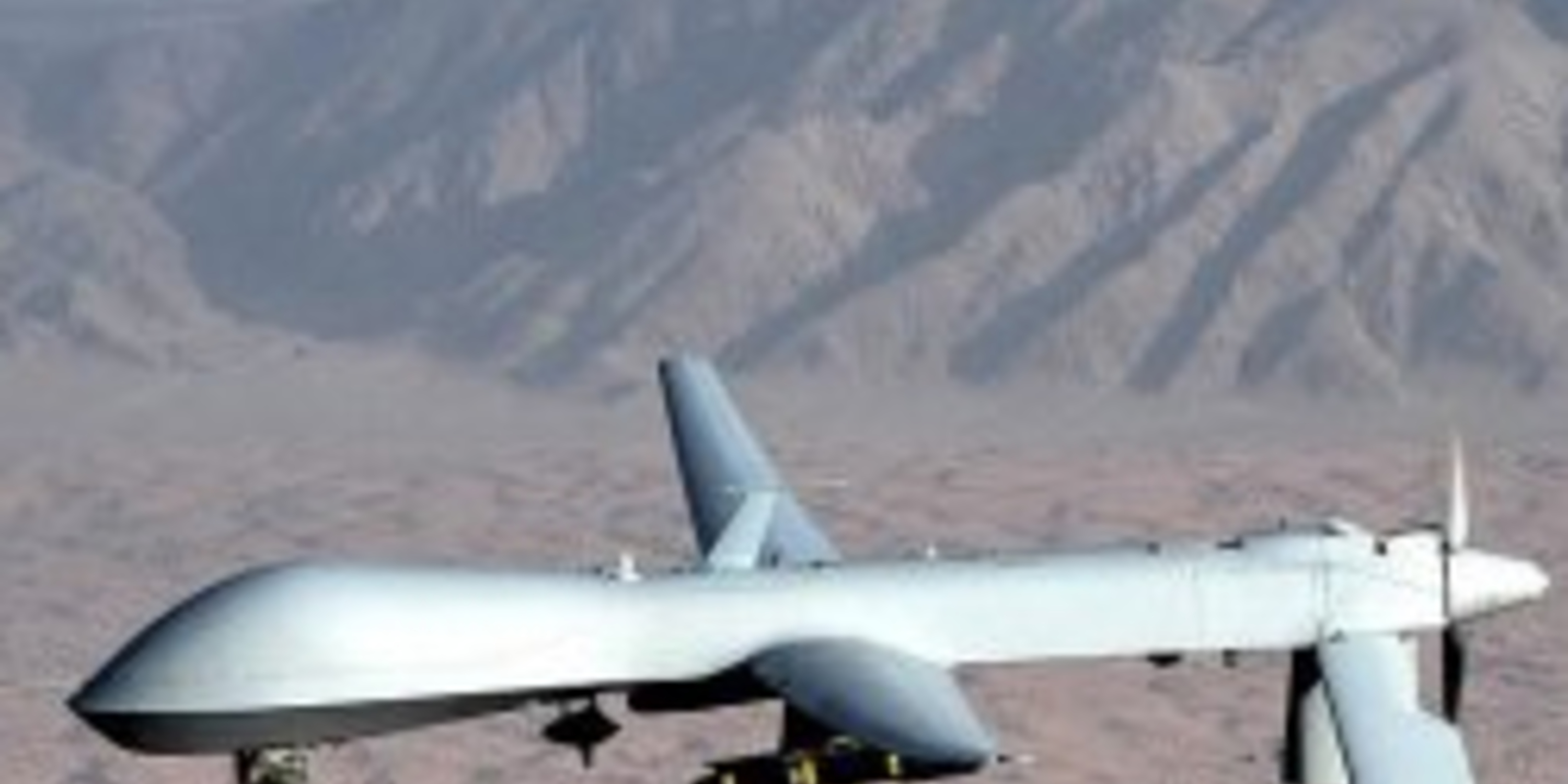 a military drone in the air over a desert