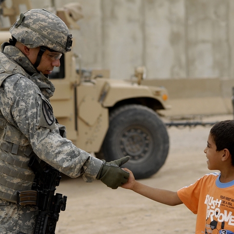 U.S. Army Maj. Robert Rodriguez shakes hands with a local child.