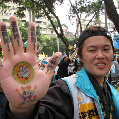 DPP supporter with hand tattoo reading, roughly, “Reverse the Tide [to triumph].”