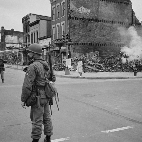 A soldier stands observing the aftermath of a race riot in Washington D.C., 1968.