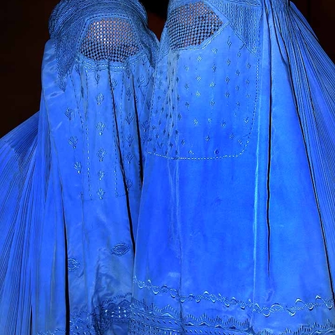 Two Afghan women dressed in bright blue burqas. Today the burqa stands as a symbol of the status of women in Afghanistan, but for much of the twentieth century the history of women in this war-torn country led also toward greater rights and public presence.