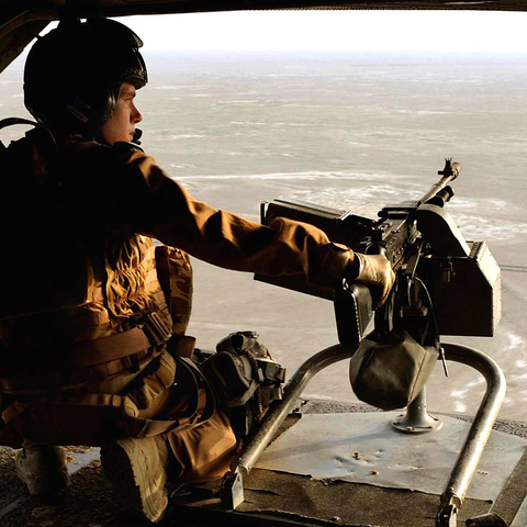 A Royal Air Force gunner kneels next to his machine gun.