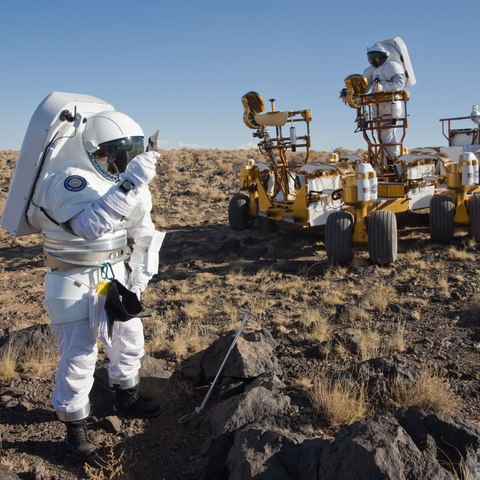 An astronaut and geologist in Arizona testing a lunar rover.