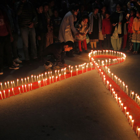 A red AIDS ribbon outlined in candles