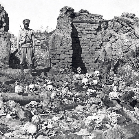 Turkish soldiers standing over skeletal remains during Armenian Genocide