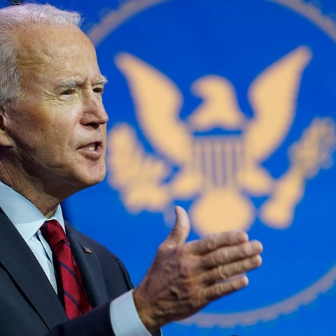 President Biden, standing in front of a blue flag with an eagle emblem