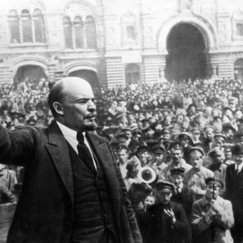 Lenin waving flag in front of crowd of workers and soldiers