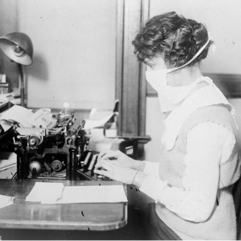 The hazards of an enclosed work environment – a typist with cloth mask during the influenza pandemic in 1918.