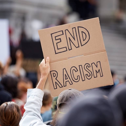 person holding up sign that reads, end racism