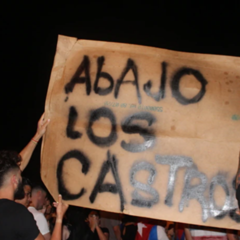 Exiles carry a poster against the communist government of Cuba, in a demonstration in Miami