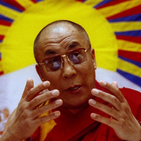 The Dalai Lama speaking in front of Tibet's flag.