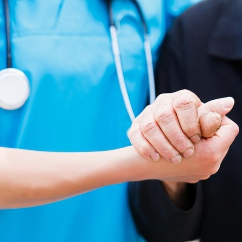 Photo of a healthcare worker holding an elderly person's hand.