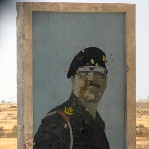 Painted poster of Saddam Hussein riddled with bullet holes in 2003.