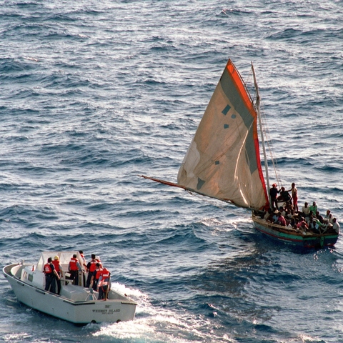 A U.S. Coast Guard boat approaches a sailboat with over 90 Haitian refugees in 1988. The refugees were later returned to Haiti.