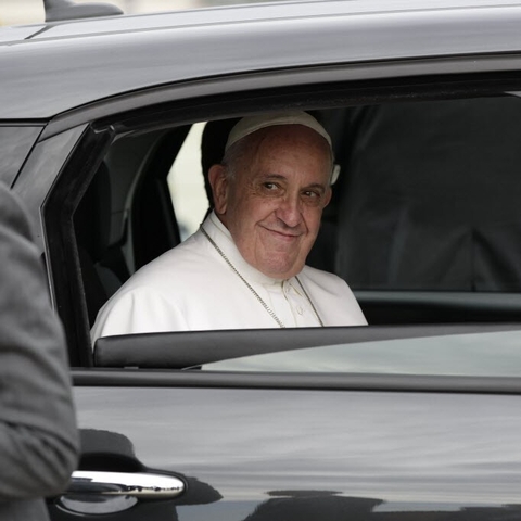 Pope Francis smiling from inside a car as he leaves the White House in 2015.