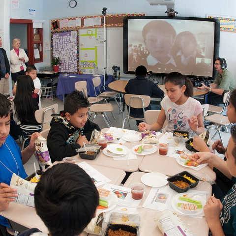 Children eating a meal as part of the School Lunch program at a classroom in Maryland. The U.S. Department of Agriculture's (USDA) Deputy Under Secretary Dr. Janey Thornton is present for an event to launch International School Meals Day on March 8, 2013. The class is video conferencing to a school in Ayrshire, Scotland, with some of their children visible on the screens.