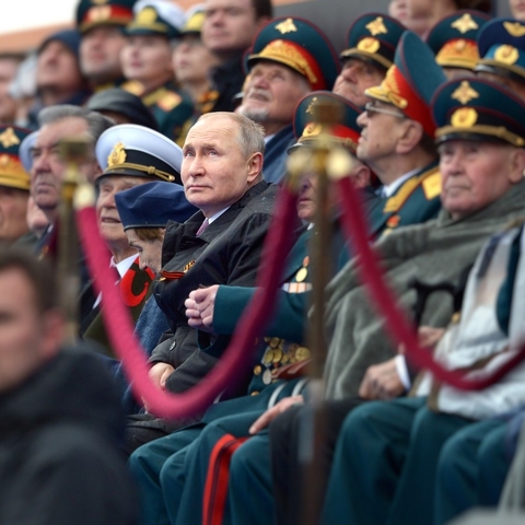 Vladimir Putin seated and surrounded by military officers