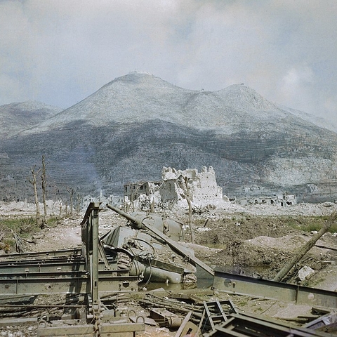 The ruins of Cassino, May 1944 - a wrecked Sherman tank and Bailey bridge in the foreground, with Monastery Ridge and Castle Hill