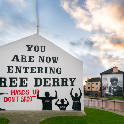 Ferry Derry Corner in Northern Ireland. Text on side of building reads You are now entering Free Derry hands up don't shoot