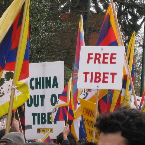 people holding signs protesting China's occupation of Tibet