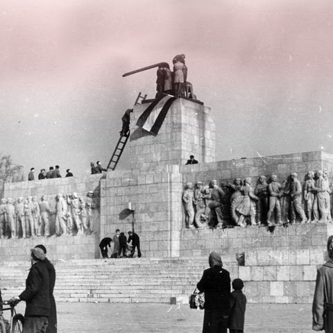 anti-communists and nationalists place a Hungarian national flag atop a demolished statue of Josef Stalin