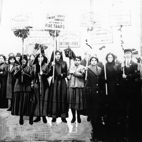 Mourners picket after the Triangle fire. Their signs, hung with black crepe, accuse shop owners of graft, locked doors, and managing workers in fire traps.