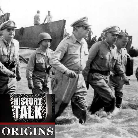 Black and white photo of General MacArthur, U.S. troops, and Philippine President Sergio Osmeña walking ashore in knee-high surf.