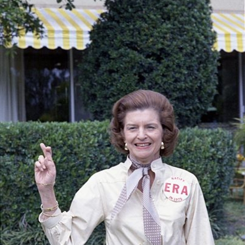 First Lady Betty Ford crossing her fingers and wearing a button in support of ratifying the Equal Rights Amendment.
