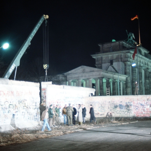 A crane removes part of the Berlin Wall in front of the Brandenburg Gate, 1989