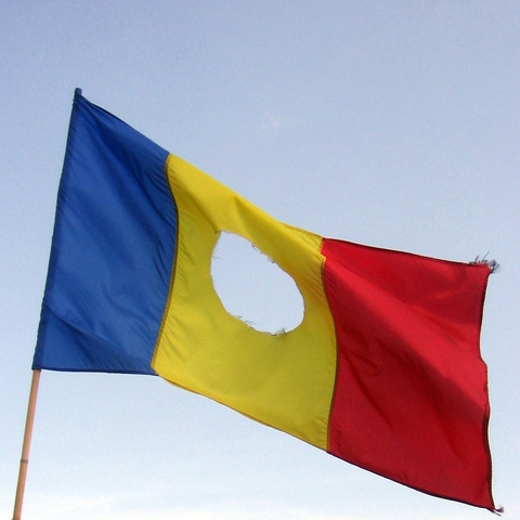 A Romanian Flag with the Soviet Symbol, the Hammer and Sickle, cut out of the center during a protest in 1989