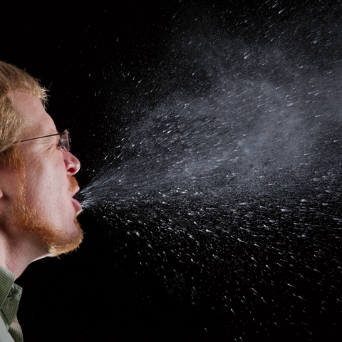 A sneeze in progress, showing the potential spread of influenza and other diseases.