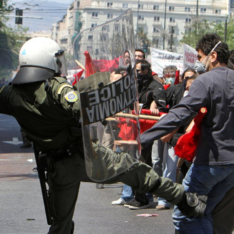 A Greek police officer kicking a protester during 2010 May Day demonstrations.