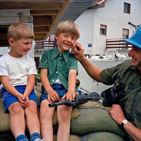 In 1992, a Canadian UNPROFOR soldier visits with two young Croatian boys, one of whom holds a toy gun.