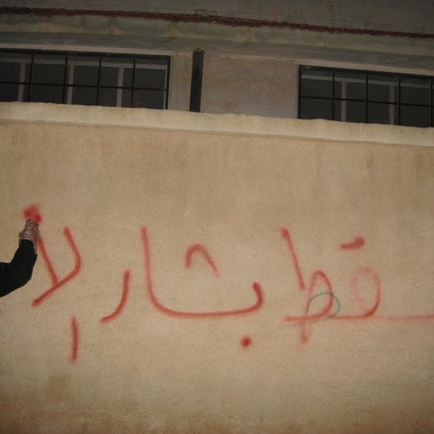 A Syrian spray-paints "Down with Bashshar" on a city wall during the 2011 uprising.