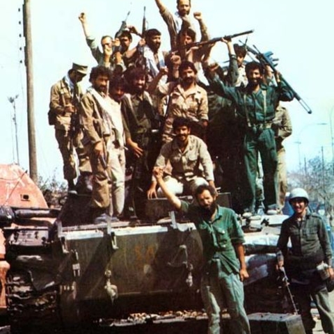 Iranian troops celebrate atop a destroyed Iraqi vehicle.