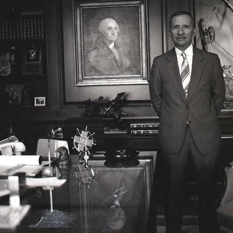 Ross Perot stands next to a portrait of George Washington.