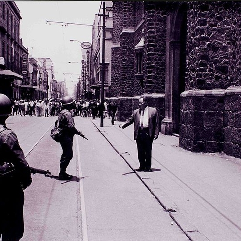 A teacher speaking with soldiers as students demonstrate in the background in July 1968 in Mexico.