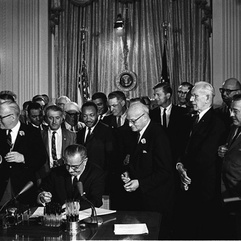Lyndon B. Johnson signs the Civil Rights Act into law in 1964.