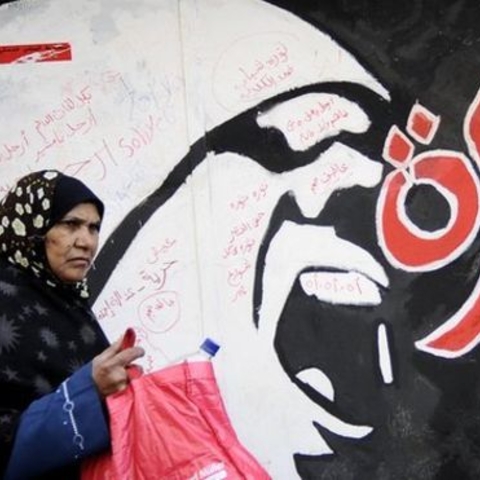 A woman walks by revolutionary graffiti in Cairo.