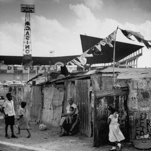A baseball stadium and casino advertisement can be seen behind these slum-like bohio dwellings.