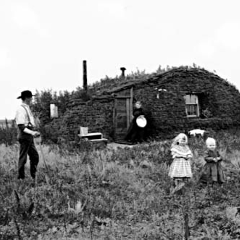 John and Marget Bakken and their two children in front of their sod house.