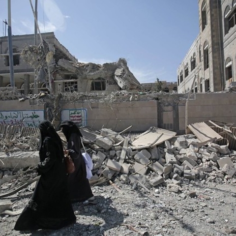 Yemenis in Sana’a passing damage from airstrikes in 2018.